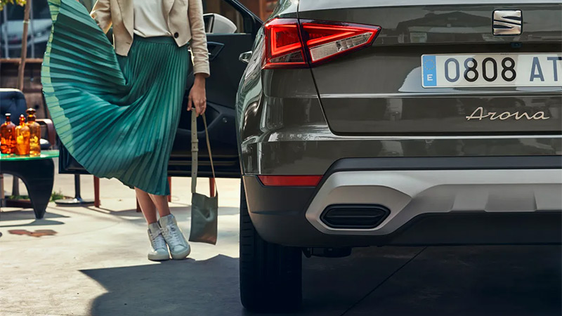 Detail na zadní nárazník vozu SEAT Arona, vedle stojí modelka v zelené sukni