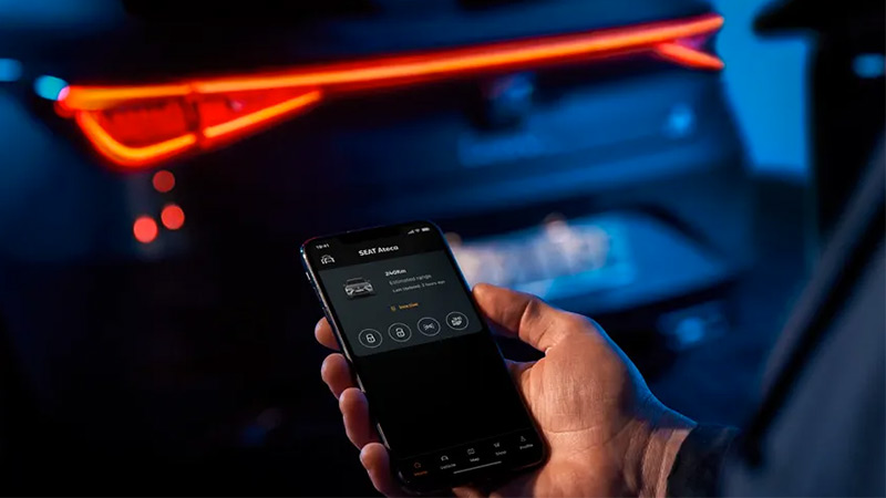 Muž drží mobil a vzdáleně se připojuje ke svému vozu SEAT Ateca