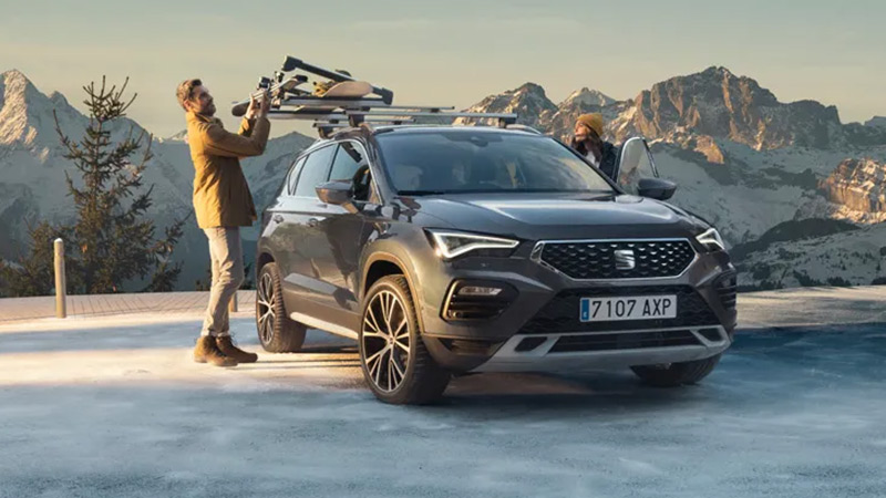 Muž nakládá lyže na nosič lyží na střeše vozu SEAT Ateca