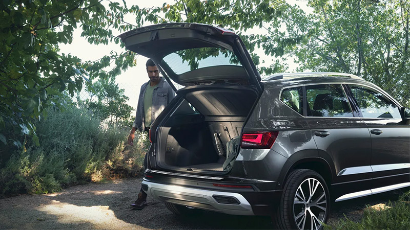 Muž jde k otevřenému zavazadlovému prostoru vozu SEAT Ateca