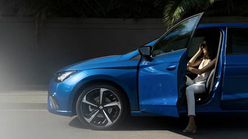 Modrý SEAT Ibiza s otevřenými dveřmi u řidiče kde sedí modelka