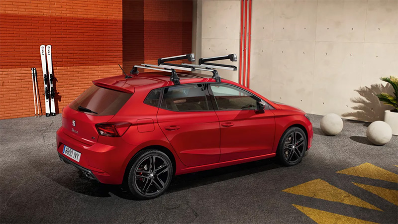 Červený vůz SEAT Ibiza se střešním nosičem lyží