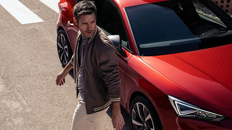 Muž prochází kolem červeného modelu vozu SEAT Leon