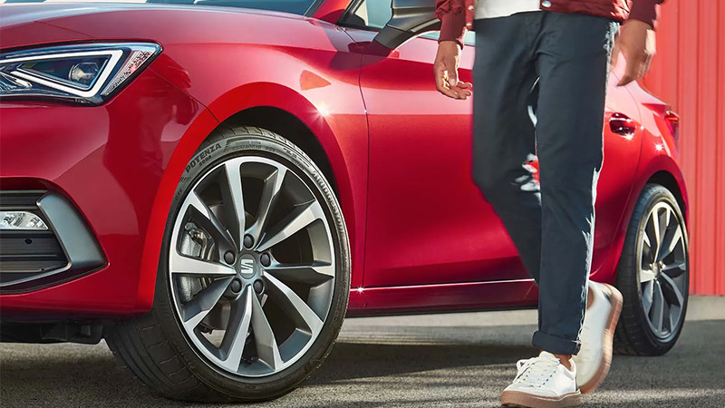Muž stojí vedle červeného vozu SEAT Leon - detail kol