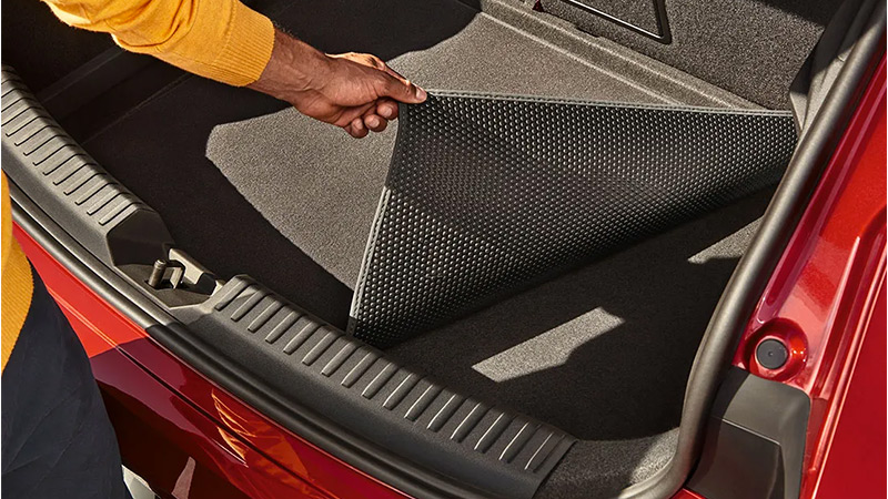 Muž ukazuje obě strany koberečku v zavazadlovém prostoru modelu SEAT Leon